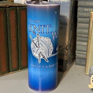 May include: A blue ombre tumbler with the text "You Say Knit, Like It's a Bad Thing" and a graphic of yarn and knitting needles. The tumbler is cylindrical and appears to be made of stainless steel, perfect for knitters.