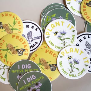 May include: A collection of round stickers with nature-themed designs. Some stickers feature text like "Plant It and They Will Come" and "I Dig Native Plants." The stickers showcase illustrations of bees, butterflies, and flowers in various colors.