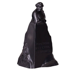 May include: Black and white sculpture of a man with a beard, standing on a pedestal with the inscription "Proletarians of all countries, unite!"