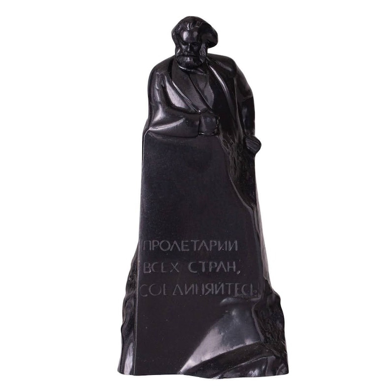 May include: Black and white statue of a man with a beard standing on a pedestal with the text "PROLETARIANS OF ALL COUNTRIES, UNITE!" inscribed on it.