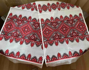 Puede incluir: Dos caminos de mesa bordados blancos con patrones geométricos rojos y negros. Los caminos de mesa tienen un borde de encaje blanco.