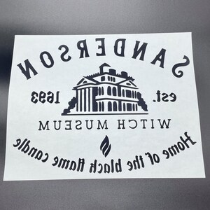 Op de afbeelding: Zwart-wit grafisch ontwerp met de tekst "SANDERSON WITCH MUSEUM est. 1933 Home of the Black Flame Candle" en een silhouet van een huis.