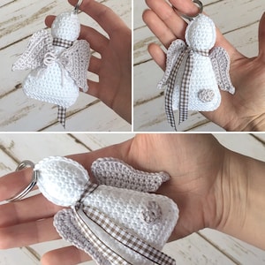 Può includere: Un portachiavi a forma di angelo all'uncinetto bianco fatto a mano con ali grigie e un nastro a scacchi marrone e bianco. L'angelo ha un piccolo dettaglio floreale e un portachiavi argentato. L'oggetto è decorativo.