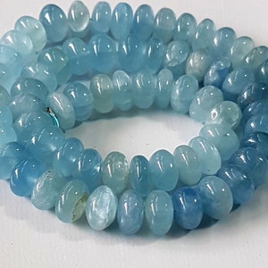 May include: A strand of light blue aquamarine beads. The beads are faceted and have a smooth, polished finish. The beads are strung on a clear elastic cord.