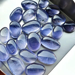 Peut inclure: Une collection de pierres précieuses ovales lisses de couleur bleu clair. Les pierres sont disposées dans un plateau en métal.
