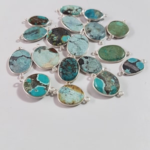 May include: A collection of oval-shaped turquoise stones with silver accents. The stones are a mix of blue, green, and brown colors.