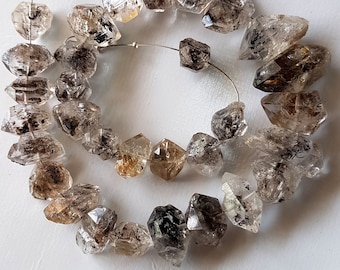May include: A strand of faceted, smoky quartz beads with a rough, natural finish. The beads are strung on a silver wire and are approximately 1/2 inch in diameter.