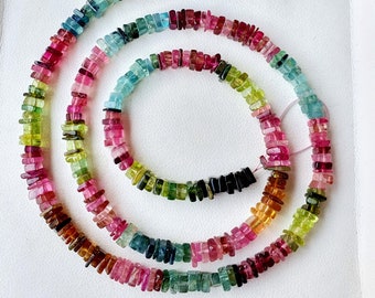 May include: A strand of multi-colored gemstone beads. The beads are square and faceted, and they are strung on a clear thread. The colors of the beads include pink, green, blue, and brown.
