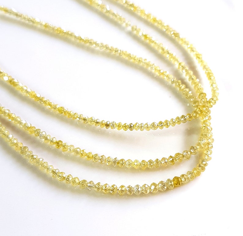 May include: A strand of yellow diamond beads. The beads are small and round, and they are strung together on a thin wire.