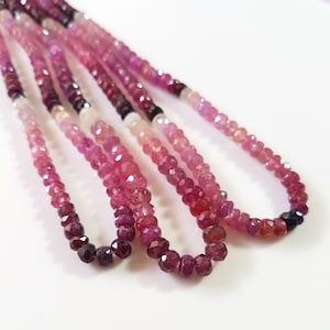 May include: A strand of pink, red, and purple gemstone beads. The beads are faceted and have a slightly irregular shape. The strand is made up of multiple rows of beads.