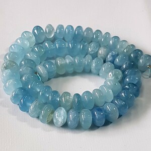 May include: A strand of light blue aquamarine beads, each bead is faceted and has a rounded shape.