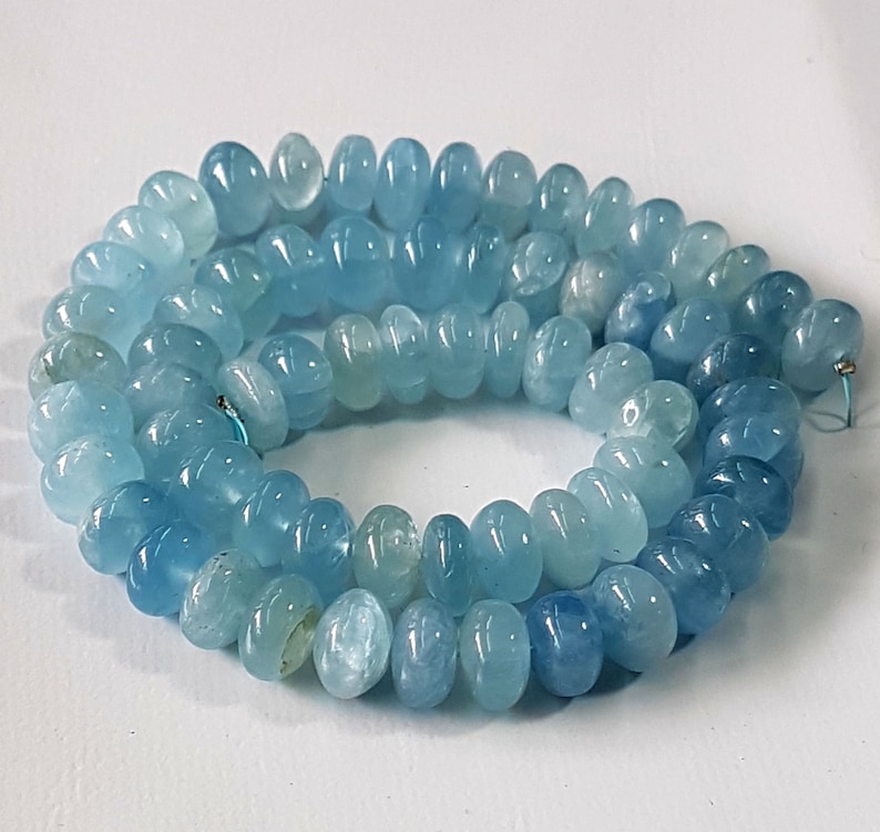 May include: A strand of light blue aquamarine beads, each bead is faceted and has a rounded shape.