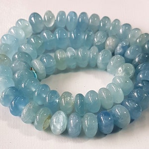 May include: A strand of light blue aquamarine gemstone beads. The beads are smooth and oval shaped.