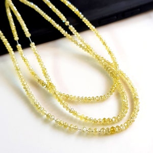 May include: A strand of yellow diamond beads, with a faceted, polished finish. The beads are strung on a clear thread and are arranged in a loose, flowing pattern.