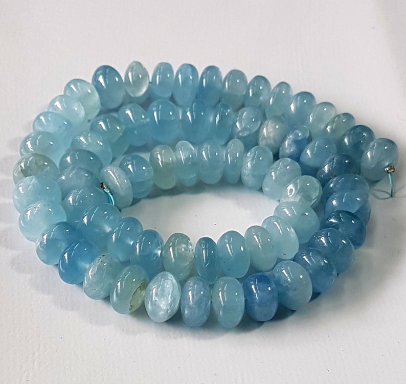 May include: A strand of light blue aquamarine beads, each bead is faceted and has a rounded shape.