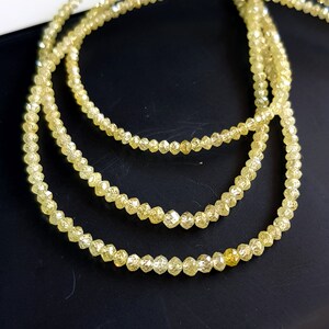 May include: A strand of yellow diamond beads, with three rows of beads, on a black background.