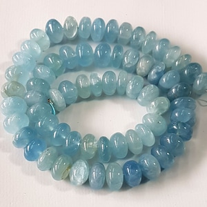 May include: A strand of light blue aquamarine gemstone beads. The beads are oval shaped and have a smooth, polished finish.