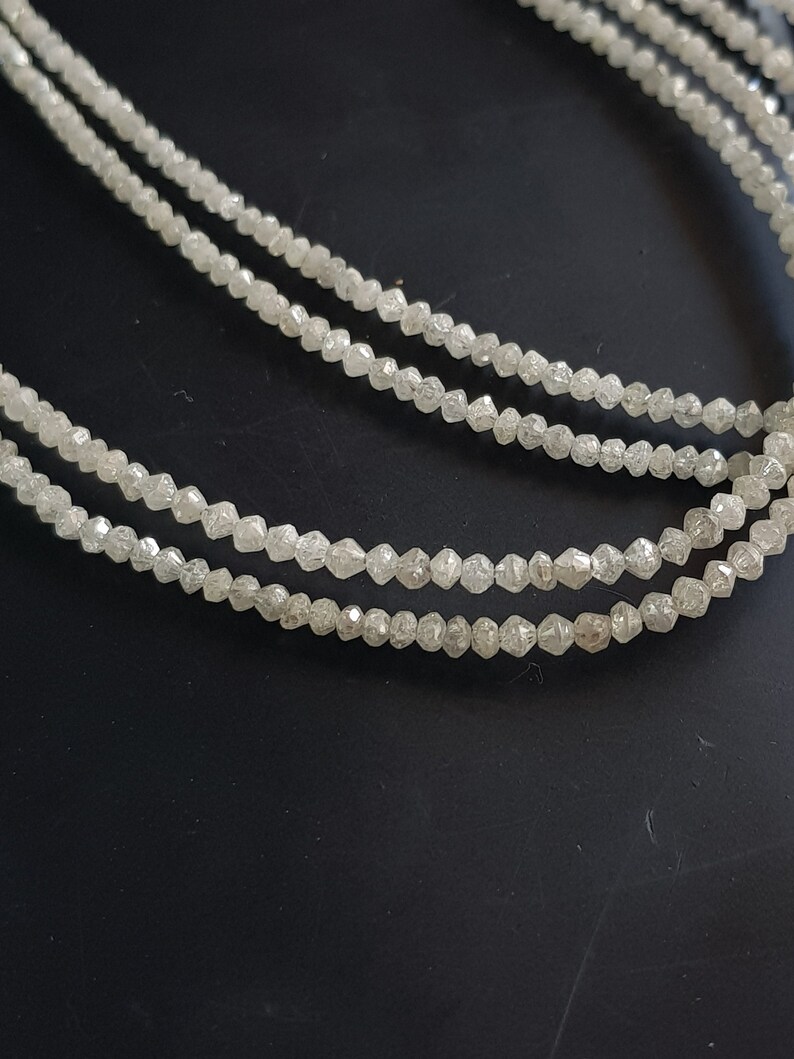 May include: A strand of white diamond beads, with each bead having a faceted, rough-cut shape.
