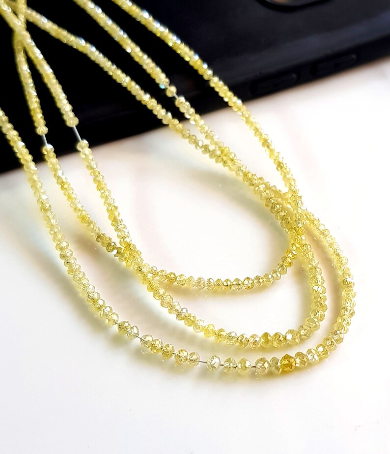 May include: A strand of yellow diamond beads, with a faceted, polished finish. The beads are strung on a clear thread and are arranged in a loose, flowing pattern.