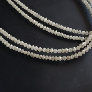 May include: A strand of white diamond beads, with each bead having a faceted, rough-cut shape.