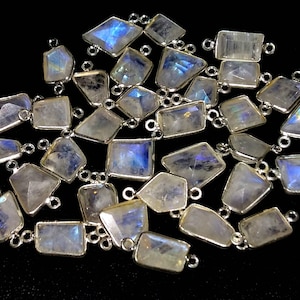 May include: A collection of iridescent rainbow moonstone gemstone connector charms with silver-toned jump rings. The stones are various shapes and sizes, with a white base and a rainbow sheen.