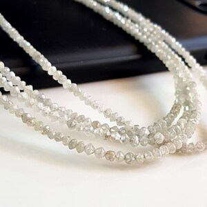 May include: A strand of white rough diamonds, strung on a thread, forming a necklace. The diamonds are small and have a natural, unpolished look.