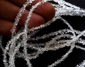 May include: A strand of clear, faceted, diamond-shaped beads. The beads are strung on a thin, clear thread. The beads are all approximately the same size and shape.