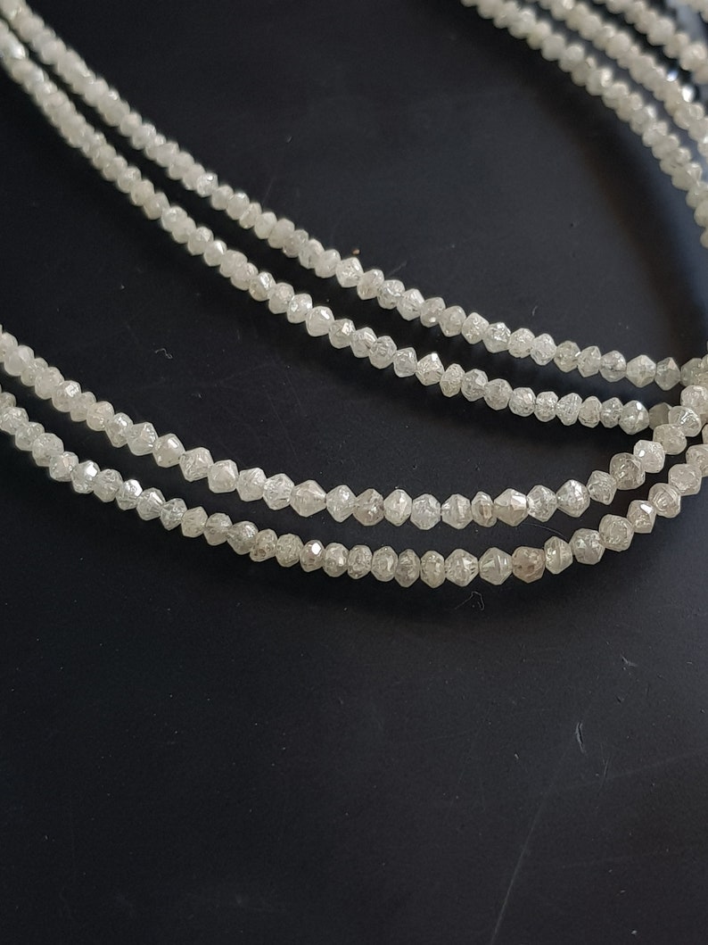 May include: A strand of white diamond beads, with each bead having a faceted, rough-cut shape.