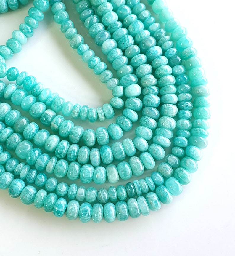 Puede incluir: Una hebra de cuentas de piedras preciosas de color verde turquesa, con un acabado liso y pulido. Las cuentas son redondas y ligeramente alargadas, creando un aspecto &uacute;nico y elegante.