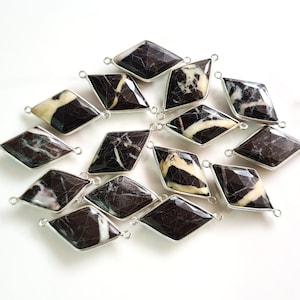May include: A collection of 15 black and white marble gemstone diamond-shaped pendants with silver jump rings.