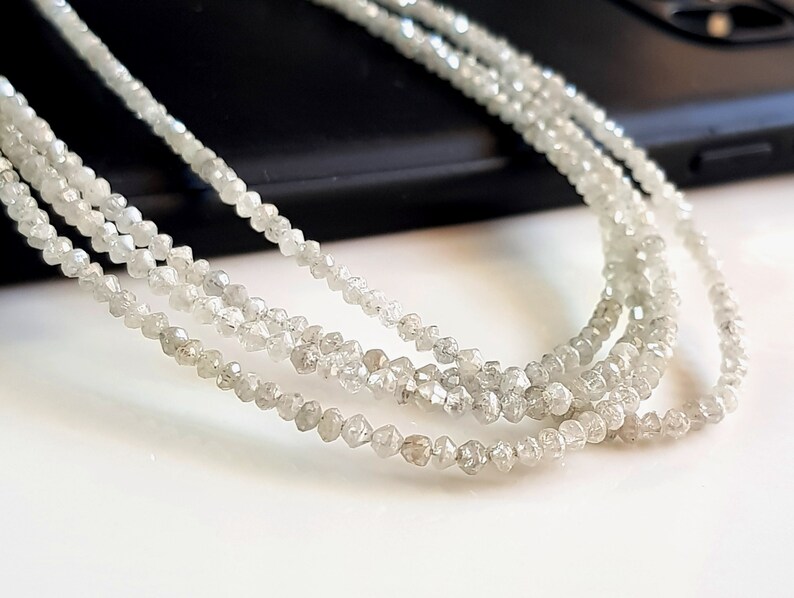 May include: A strand of white rough diamond beads. The beads are small and have a natural, unpolished look.
