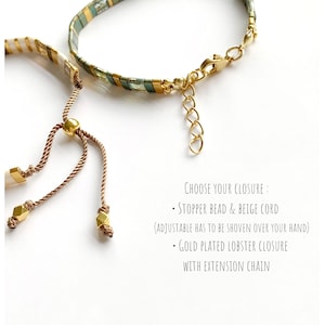 May include: Two bracelets with different closures. One features a beige cord with a gold stopper bead. The other has a gold-plated lobster clasp and extension chain. Text reads: Choose your closure: Stopper bead & beige cord (adjustable has to be shoven over your hand) - Gold plated lobster closure with extension chain.