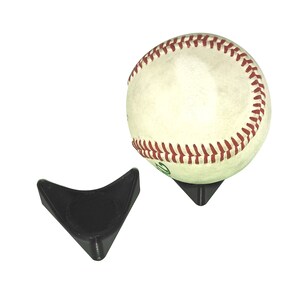May include: A white baseball with red stitching sits on a black plastic display stand. The stand is shaped like a triangle with a rounded base.