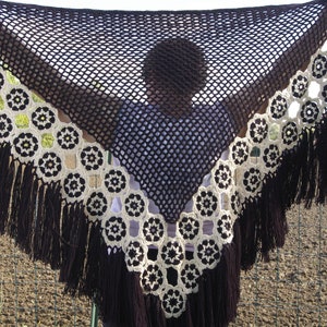 Peut inclure: Un châle en crochet marron avec une bordure et des franges en crochet blanc. Le châle présente un motif géométrique avec des motifs circulaires.