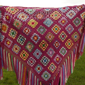 Peut inclure: Un châle en crochet rose avec des carrés de grand-mère colorés et des franges. Le châle est fait de plusieurs couleurs, dont le rose, le rouge, le bleu, le vert, le jaune et le blanc.