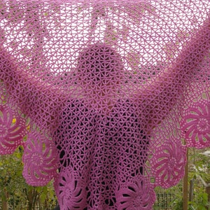 May include: A pink crocheted shawl with a delicate floral pattern. The shawl is draped over a person's shoulders, creating a soft and elegant look.