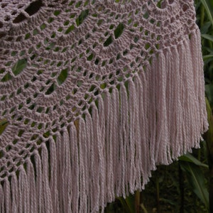May include: A crocheted shawl with a delicate pattern and a fringe border. The shawl is a light pink color.