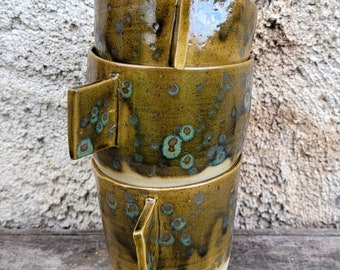 Large clay mugs with delicate handle in khaki stained with blue and green