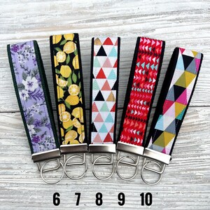 Peut inclure: Cinq porte-cl&eacute;s de poignet en tissu avec diff&eacute;rents motifs : floral, citrons, triangles, formes g&eacute;om&eacute;triques rouges et formes g&eacute;om&eacute;triques color&eacute;es. Chaque porte-cl&eacute;s a un anneau en m&eacute;tal argent&eacute; et un dos noir. Les chiffres 6, 7, 8, 9 et 10 sont imprim&eacute;s en dessous.