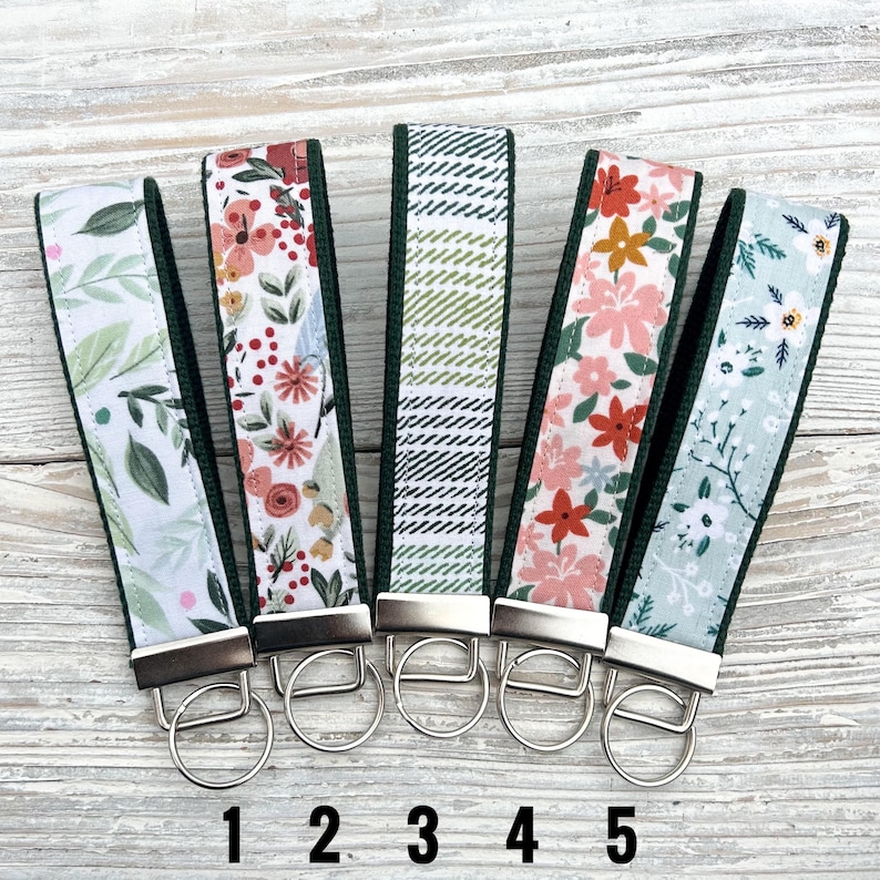 Peut inclure: Cinq porte-cl&eacute;s en tissu avec diff&eacute;rents motifs floraux et g&eacute;om&eacute;triques. Chaque porte-cl&eacute;s a une bordure vert fonc&eacute;, un porte-cl&eacute;s en m&eacute;tal argent&eacute; et un motif en tissu assorti. Les porte-cl&eacute;s sont num&eacute;rot&eacute;s de 1 &agrave; 5.