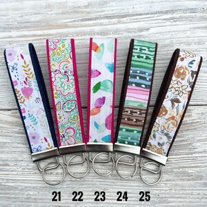 Peut inclure: Cinq porte-cl&eacute;s en tissu avec diff&eacute;rents motifs et couleurs. Les motifs comprennent des motifs floraux, cachemire et abstraits. Chaque porte-cl&eacute;s a un anneau en m&eacute;tal argent&eacute; et un dos en tissu assorti. Les num&eacute;ros 21, 22, 23, 24 et 25 sont imprim&eacute;s en bas.