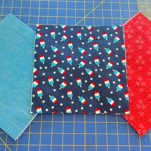 May include: Three fabric squares, one blue, one red with white stars, and one navy blue with white stars and red and white popsicle designs.