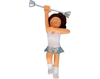 May include: A figurine of a person twirling a baton. The figure is wearing a white leotard with a silver glitter skirt and white boots. The baton is silver with silver ends. The figure has brown hair and a smiling face.