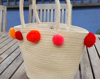 Pompom trim natural coloured, short handled basket.