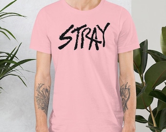May include: A pink t-shirt with a black graphic that says "STRAY" in a stylized font.