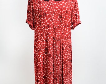 May include: A red dress with a white background and a black and red geometric pattern. The dress has a v-neck and short sleeves.