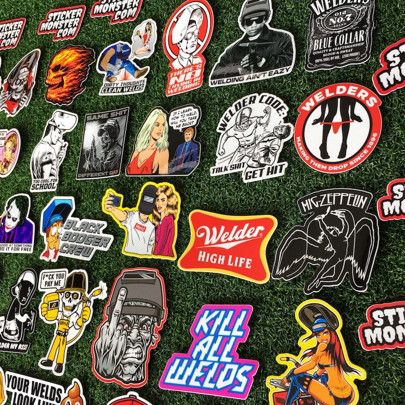 Op de afbeelding: Een verzameling kleurrijke stickers met verschillende ontwerpen, waaronder schedels, lasgerelateerde afbeeldingen en een cartoonfiguur met een middelvinger. De stickers zijn gerangschikt op een groene grasmat.