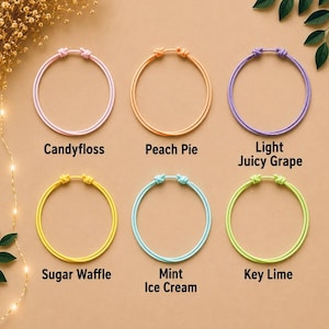 May include: Six circular cord bracelets in pastel colours labelled Candyfloss, Peach Pie, Light Juicy Grape, Sugar Waffle, Mint Ice Cream, and Key Lime. Each bracelet features a simple knotted closure and a smooth, rounded cord design.