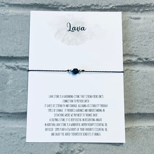 May include: Black lava stone bracelet on a white card with the word "Lava" written in black. The card describes the grounding properties of lava stone and its use in aromatherapy.