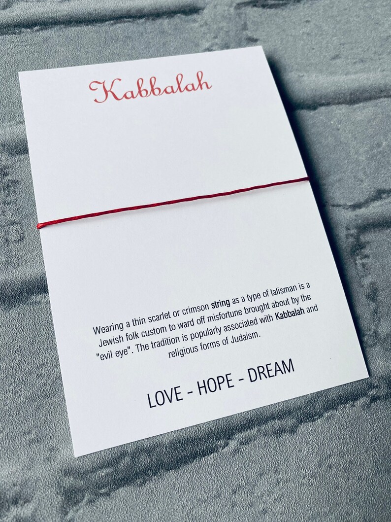 Pode incluir: Pulseira de corda vermelha com a palavra "Kabbalah" e o texto "Usar um fio fino escarlate ou carmesim como um tipo de talism&atilde; &eacute; um costume popular judeu para evitar a m&aacute; sorte causada pelo "mau-olhado". A tradi&ccedil;&atilde;o &eacute; popularmente associada &agrave; Cabala e &agrave;s formas religiosas do juda&iacute;smo. LOVE - HOPE - DREAM"